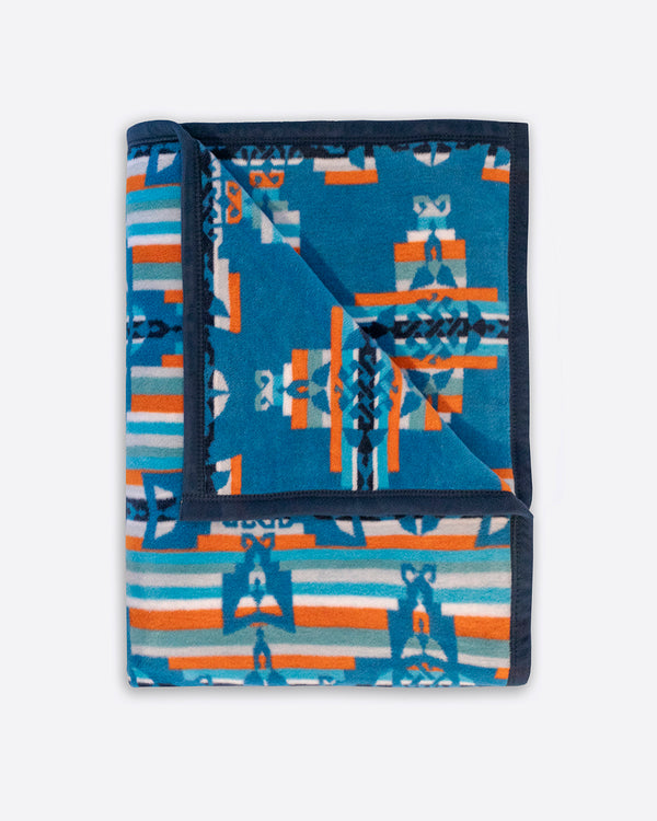 Reverse side of mother and child brown blanket. Blue and orange stripes on the background, on top are repeated geometric white mother and child symbols in a shape of a cross