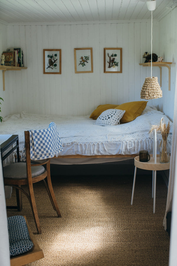 Checkered blue and white blanket folded on a back of a chair in a summer cabin room