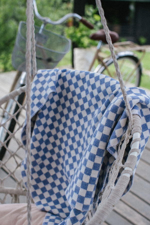 Checkered dark blue and white blanket on a white swing