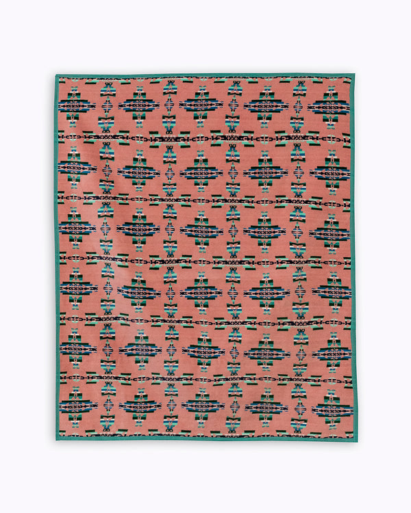 Pick background blanket with geometric green and dark green patterns that resemble crosses, 5 across and 6 vertically. Crosses are made from the Celtic mother and child symbol reimagined geometrically with corners