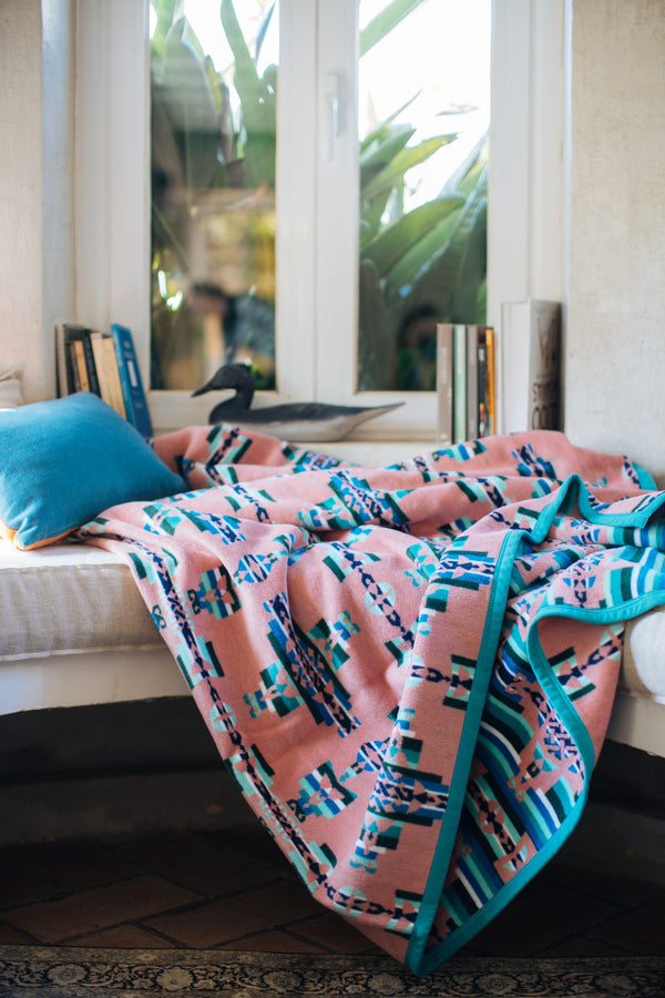 Pink and Green blanket on a window seat with geometric symbol of mother and child 