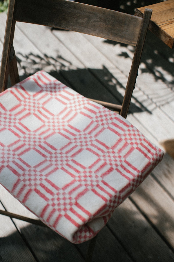 Folded red and white blanket folded on a deck chair summer light and tree shades falling around the chair